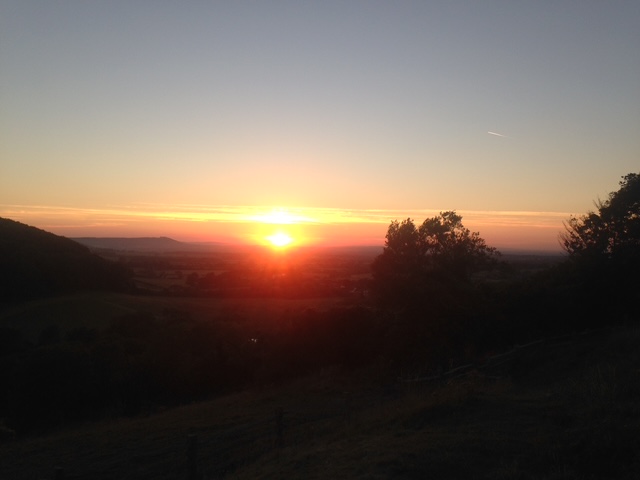 A golden sunset settling over hills and the darkening landscape